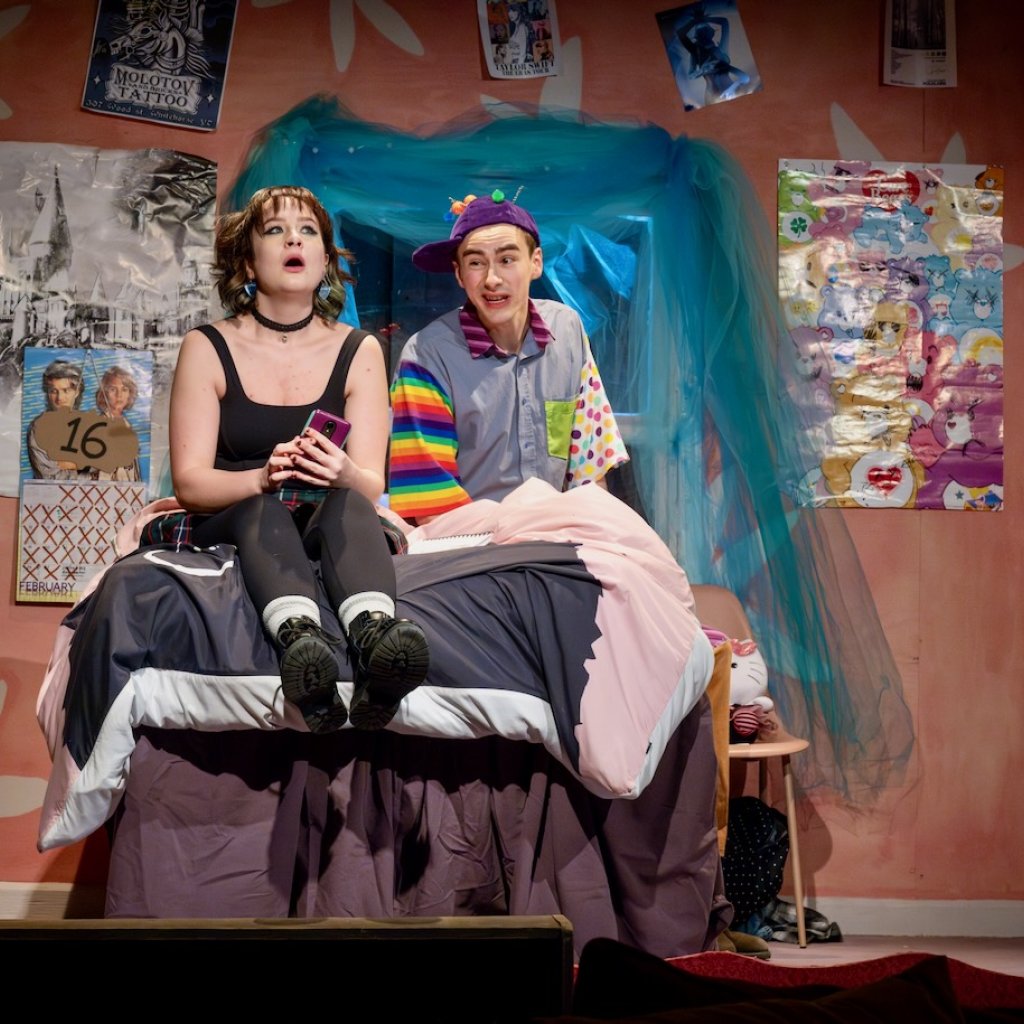 A man in a silly outfit makes a face at a young woman who is rolling her eyes in response
