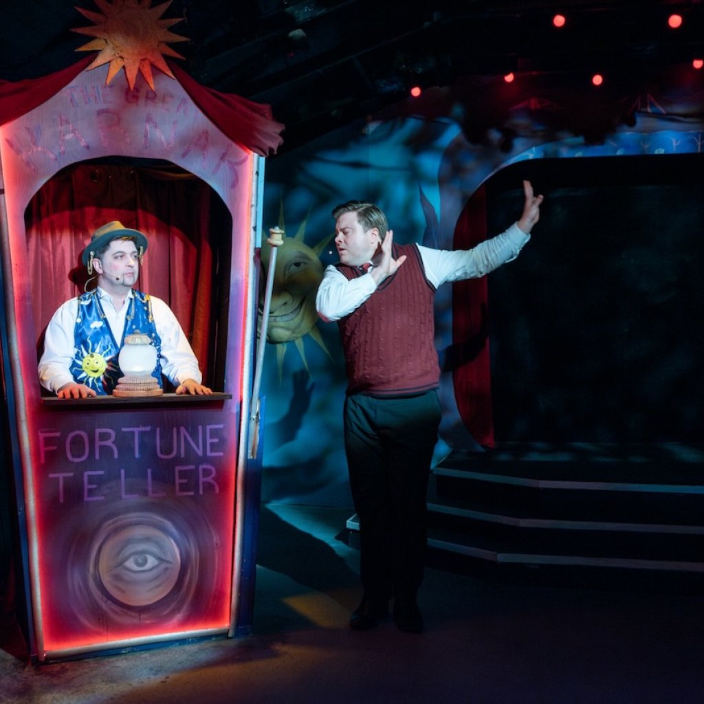 Archive photo of Ride the Cyclone. A young man standing next to a fortune telling booth.