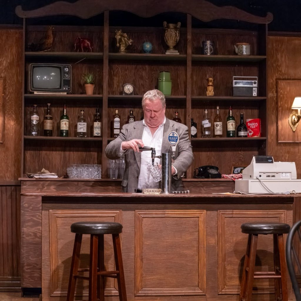 A pouring beer from a tap behind a bar