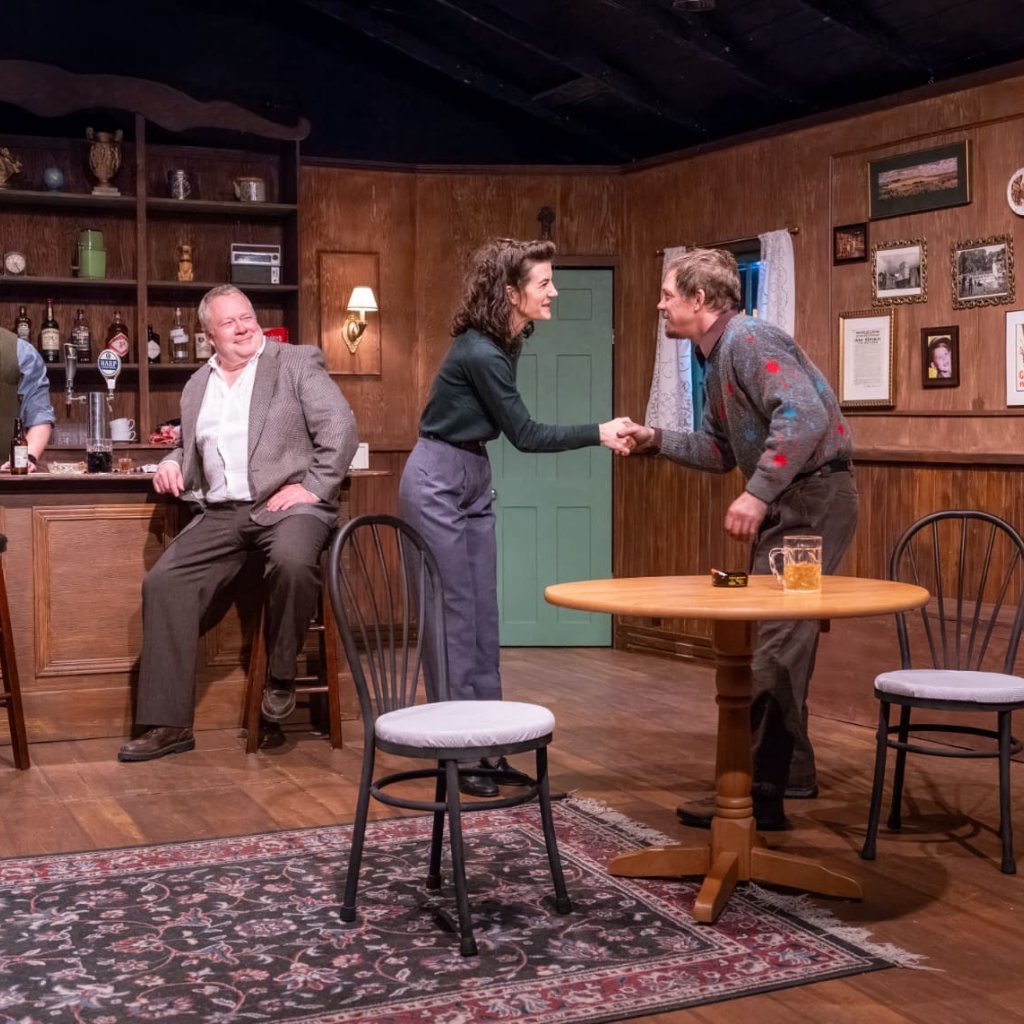 Four people in a pub. A man and woman shaking hands.
