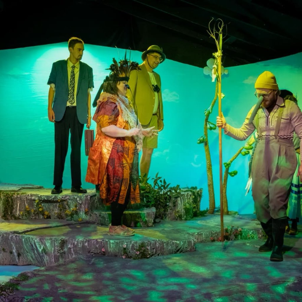Several characters dressed as birds walking around two men