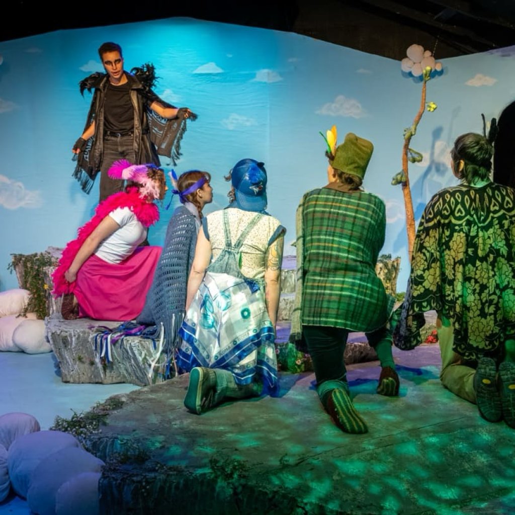 A group of people dressed as birds surrounding two men