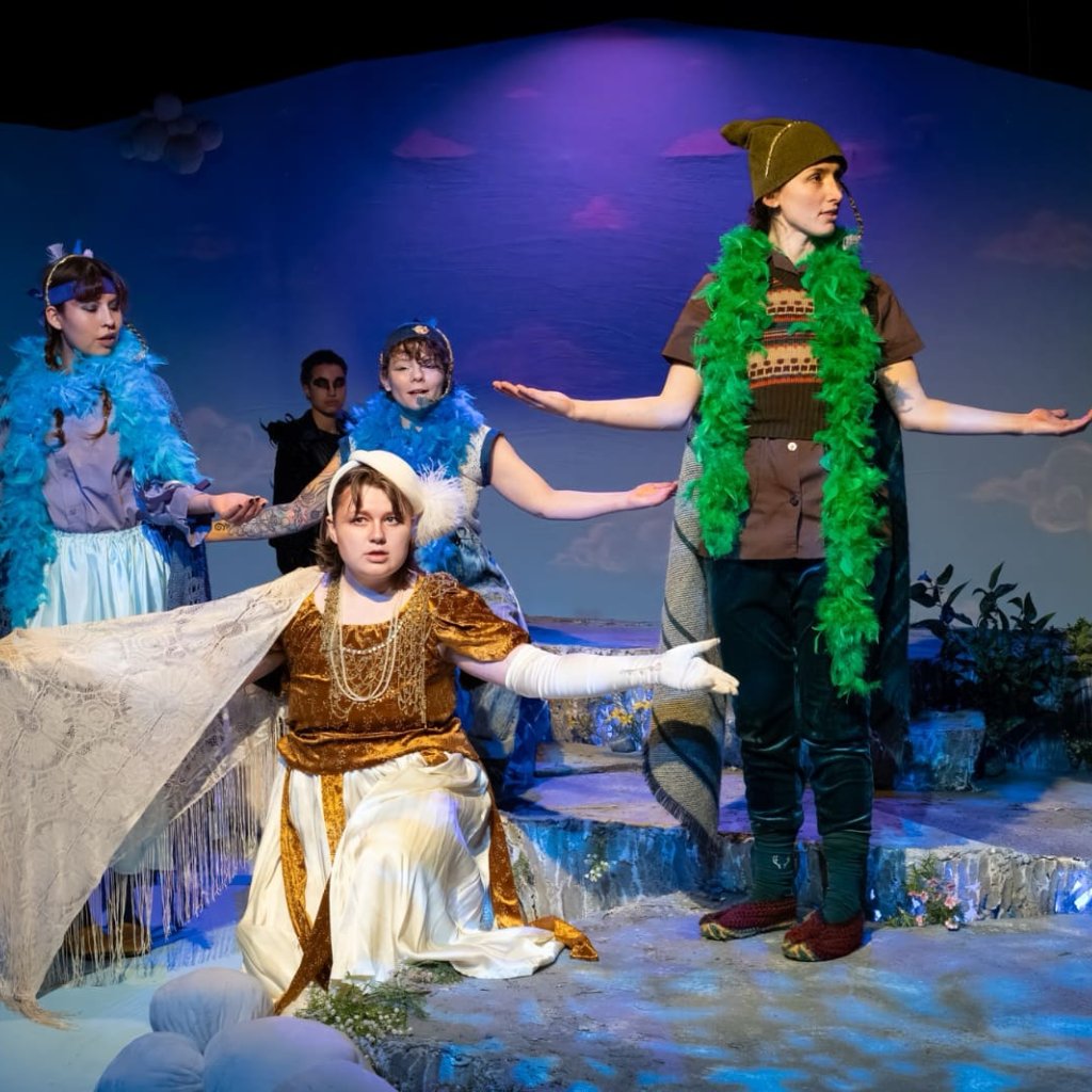 Four people dressed as birds singing with arms outspread