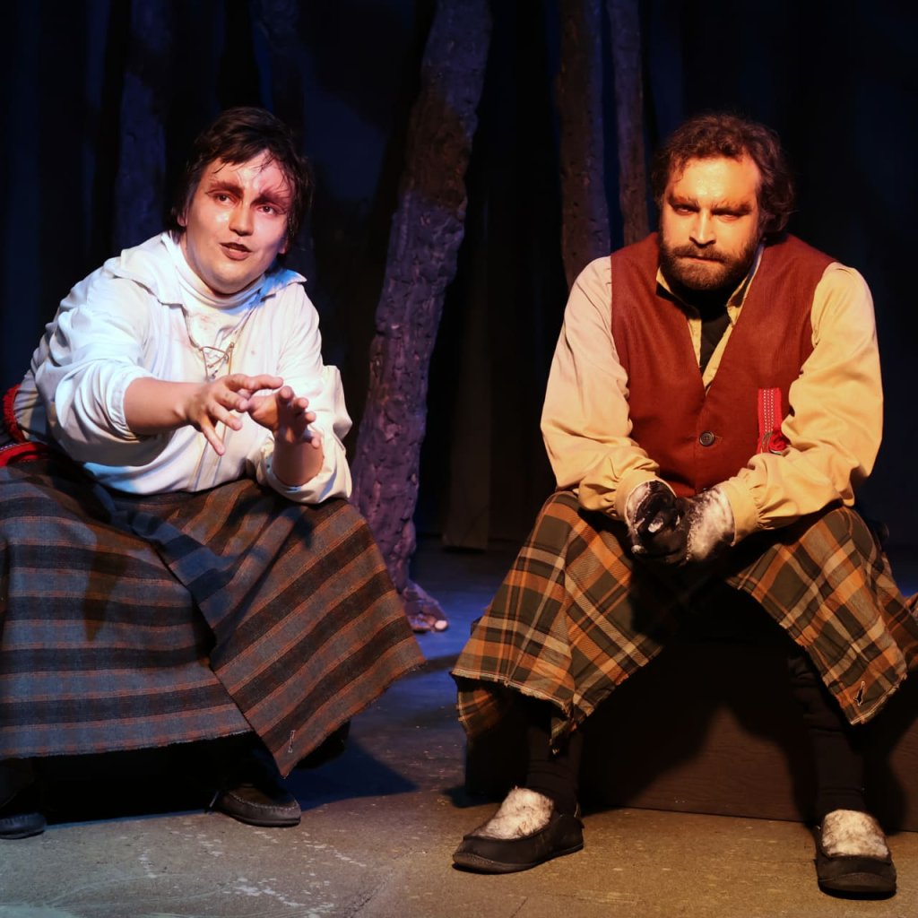 Two characters from Coy Wolf, seated and in conversation.